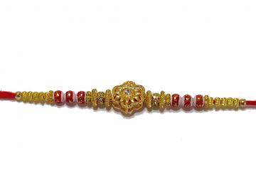 RAKHI Designed With a Golden Flower Red Beads and White Diamonds RAKHI Designed With a Golden Flower Red Beads and White Diamonds