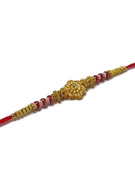 RAKHI Designed With a Golden Flower Red Beads and White Diamonds RAKHI Designed With a Golden Flower Red Beads and White Diamonds