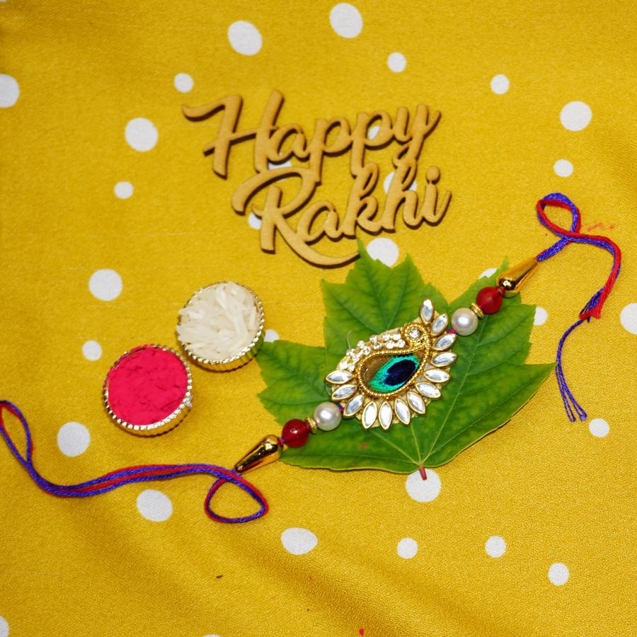 Designer Peacock Fearthe Rakhi Surrounded by Kundan + Roli & Chaval Designer Peacock Fearthe Rakhi Surrounded by Kundan + Roli & Chaval