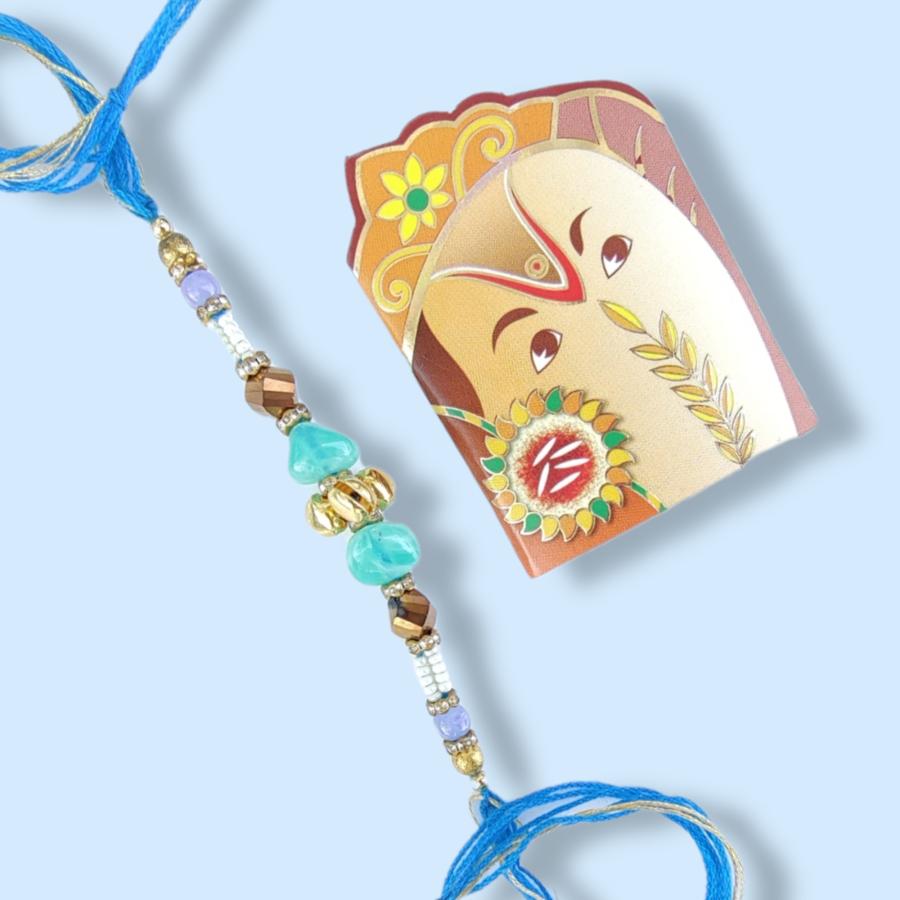 Adorable Blue Pebble Rakhi With Golden Ghungroo + Roli & Chaval Adorable Blue Pebble Rakhi With Golden Ghungroo + Roli & Chaval