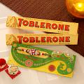 Stone Work Rakhi w/ Pack of Two Toblerone Chocolates Stone Work Rakhi w/ Pack of Two Toblerone Chocolates